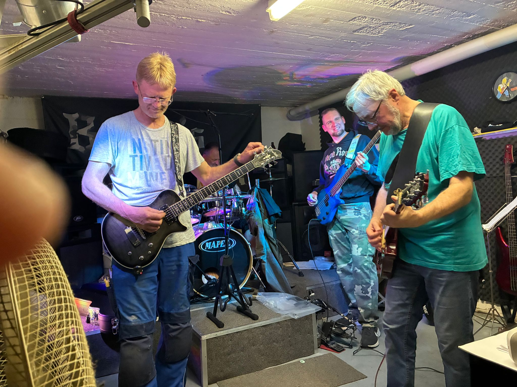 Bandmitglieder spielen gemeinsam Gitarre und Bass im Proberaum