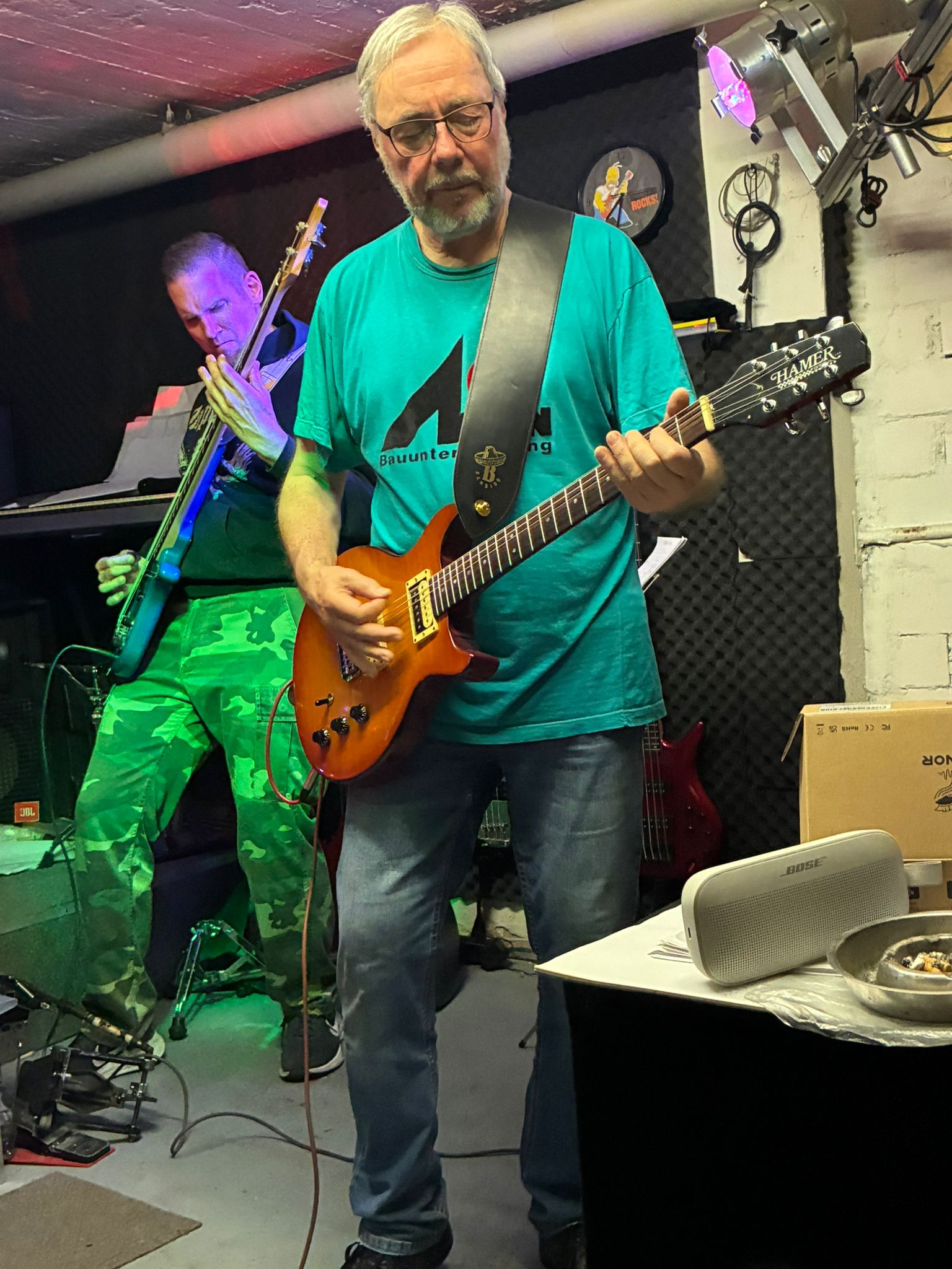 Gitarrist mit E-Gitarre bei einer Probe unter grünem und violettem Licht