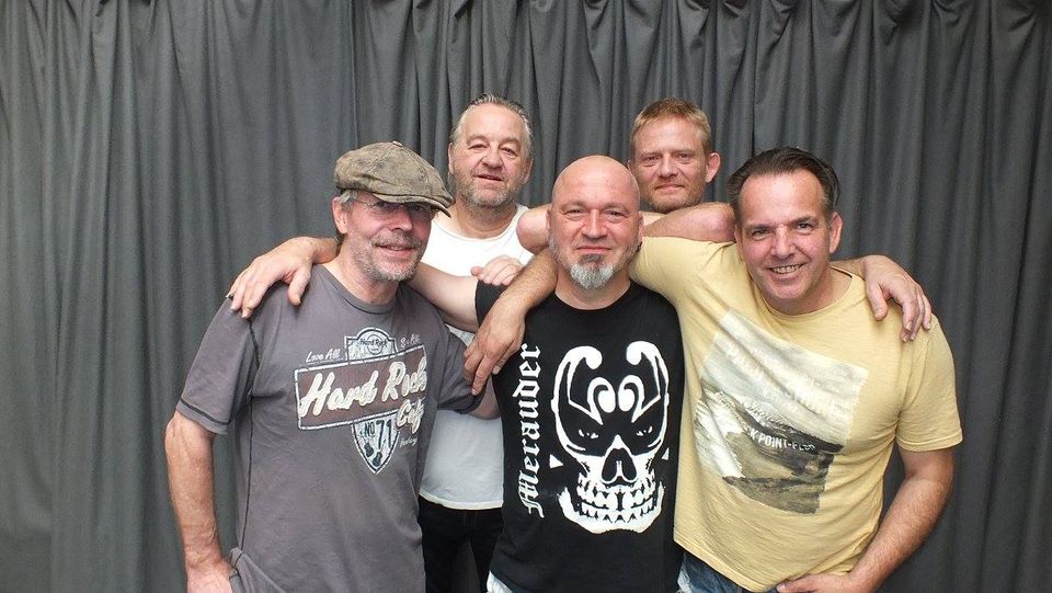 Bandmitglieder spielen gemeinsam Gitarre und Bass im Proberaum